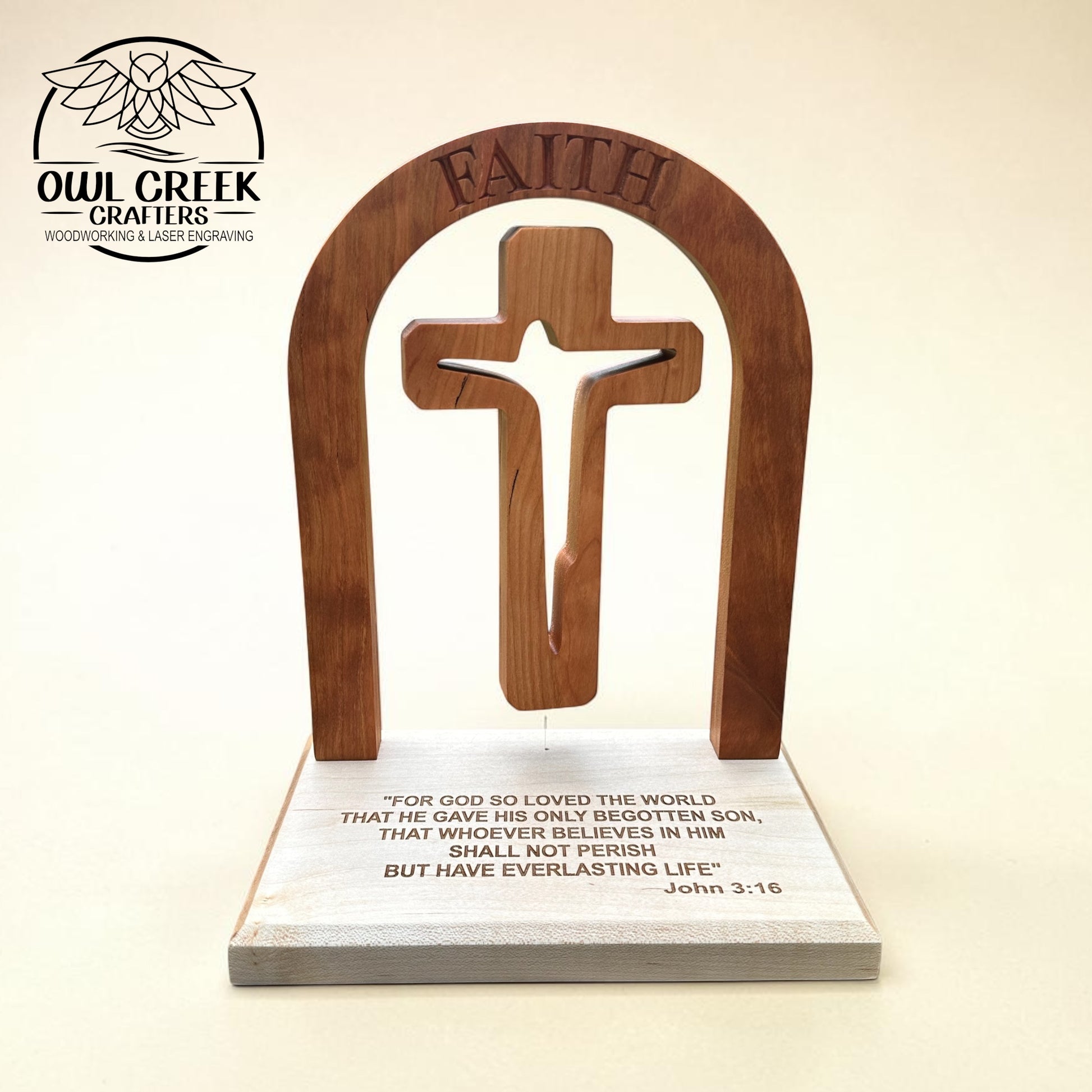 A wooden Christian altar plaque featuring an arched cherry wood cross with the word 'FAITH' engraved at the top, mounted on a rectangular maple wood base with a Bible verse printed on it. The product is photographed against a plain beige background, with the Owl Creek Crafters logo in the upper left corner.