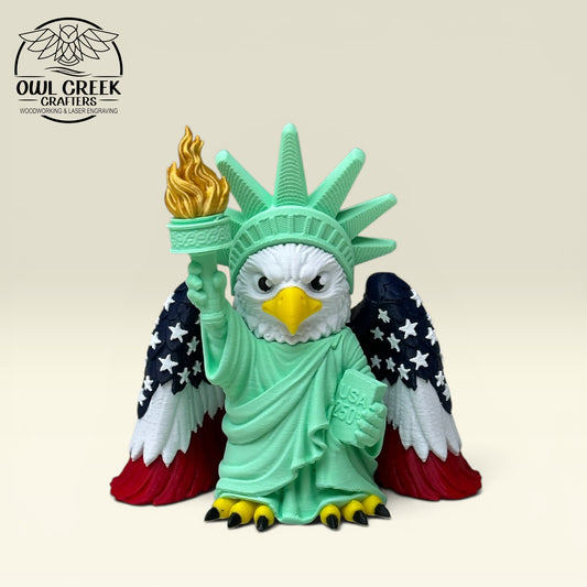 Bald eagle dressed as the Statue of Liberty with American flag wings, with a beige background and the Owl Creek Crafters Logo