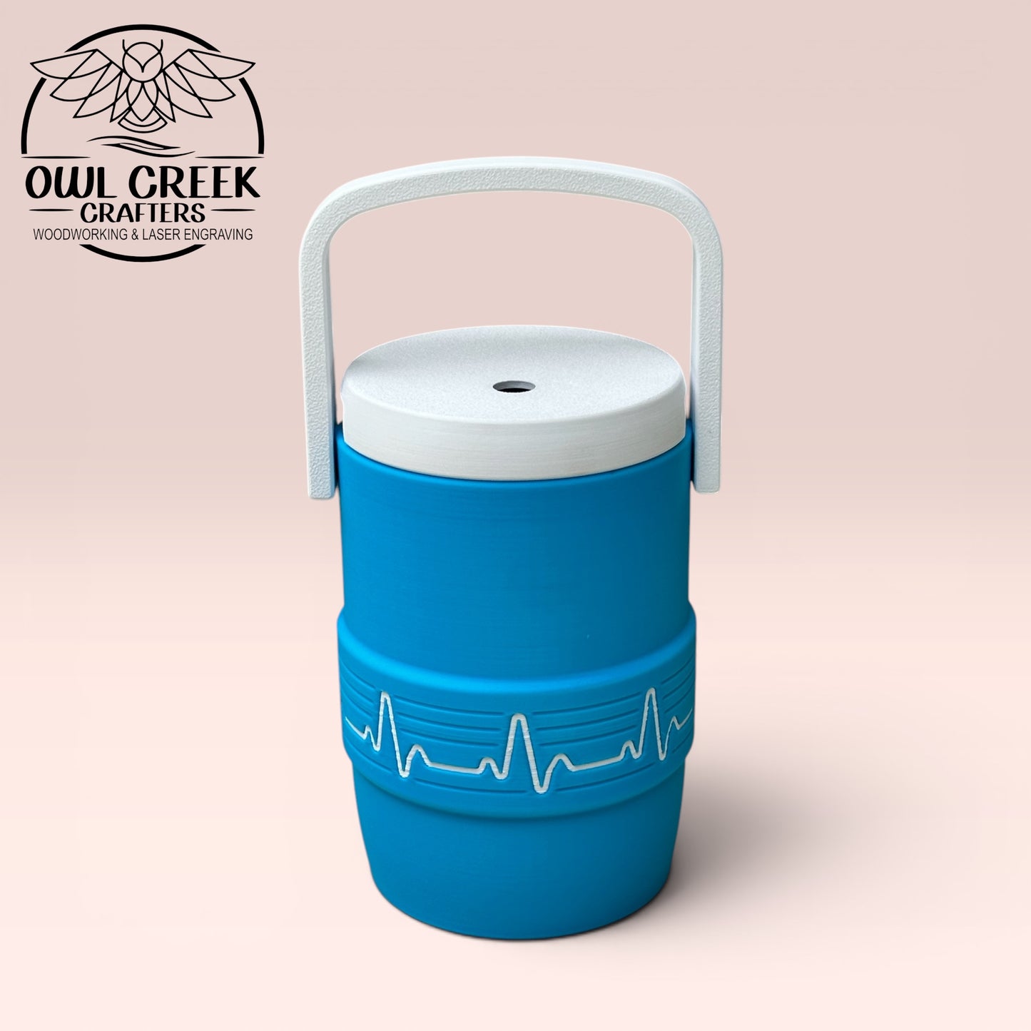 Blue can cooler coozie with a white EKG design, and a white handle and lid on a beige background, featuring the Owl Greek Crafters logo.