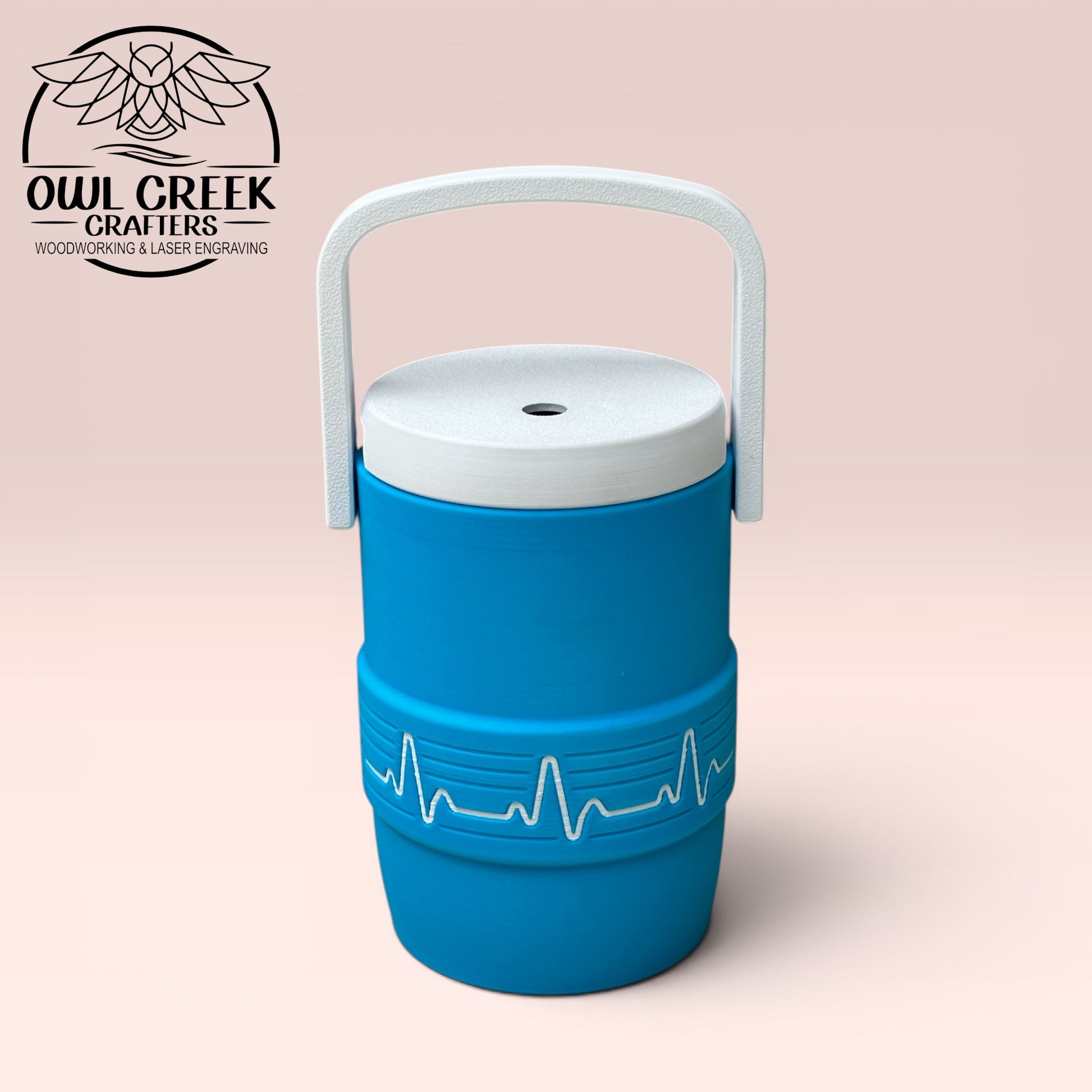 Blue can cooler coozie with a white EKG design, and a white handle and lid on a beige background, featuring the Owl Greek Crafters logo.