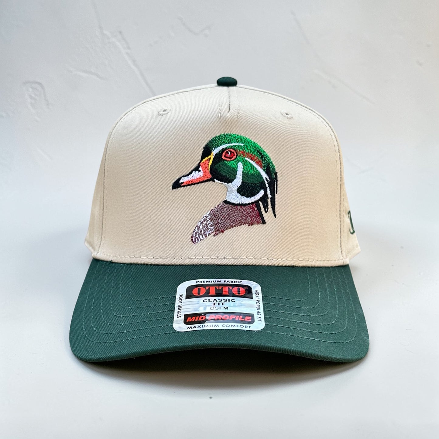 Tan and dark green cap with an embroidered wood duck design on a white background