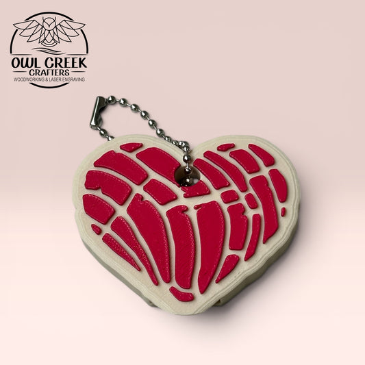 Heart-shaped keychain with magenta design on a beige background, and a 'Owl Creek Crafters' Logo