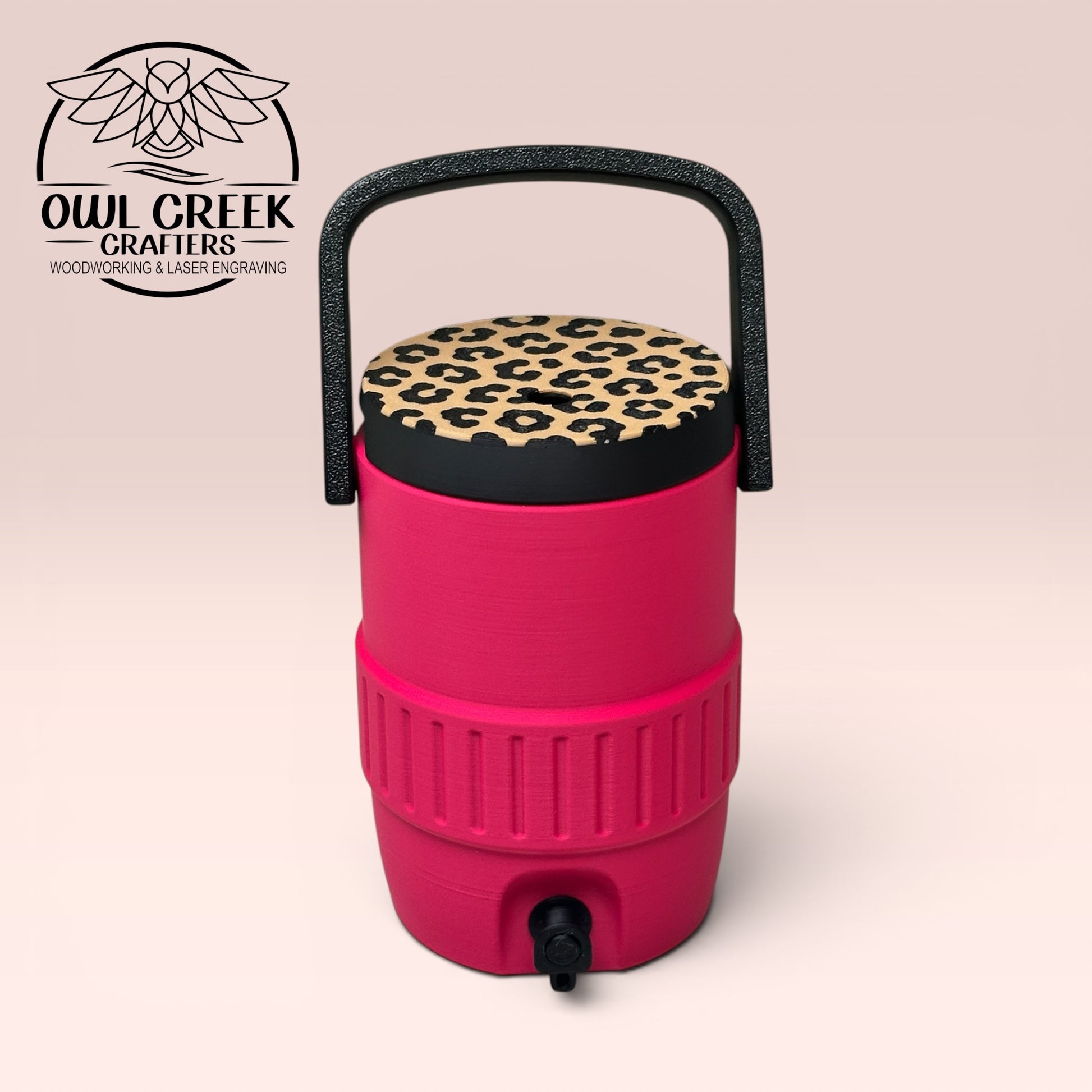 Pink can cooler coozie with leopard print lid, a black handle, on a beige background with the Owl Creek Crafters logo.