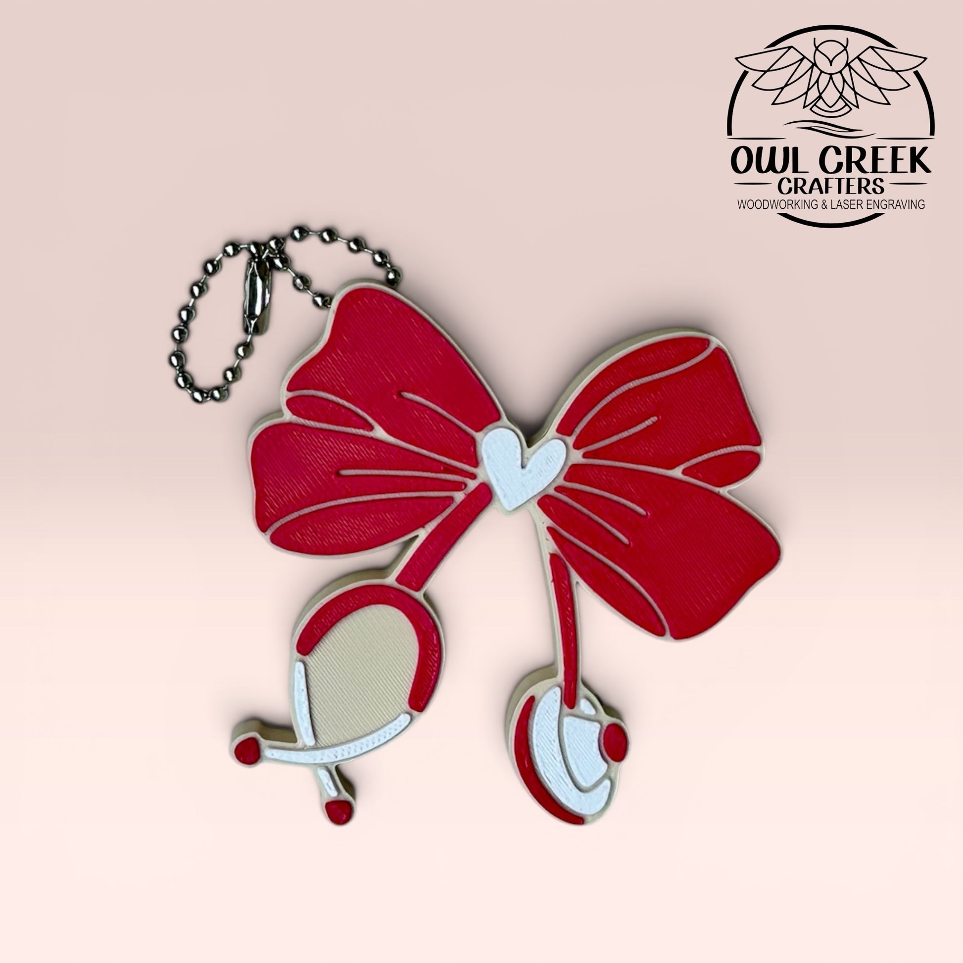 Magenta, white, and beige can opener keychain with a stethescope bow design, on a beige background with the Owl Creek Crafers Logo