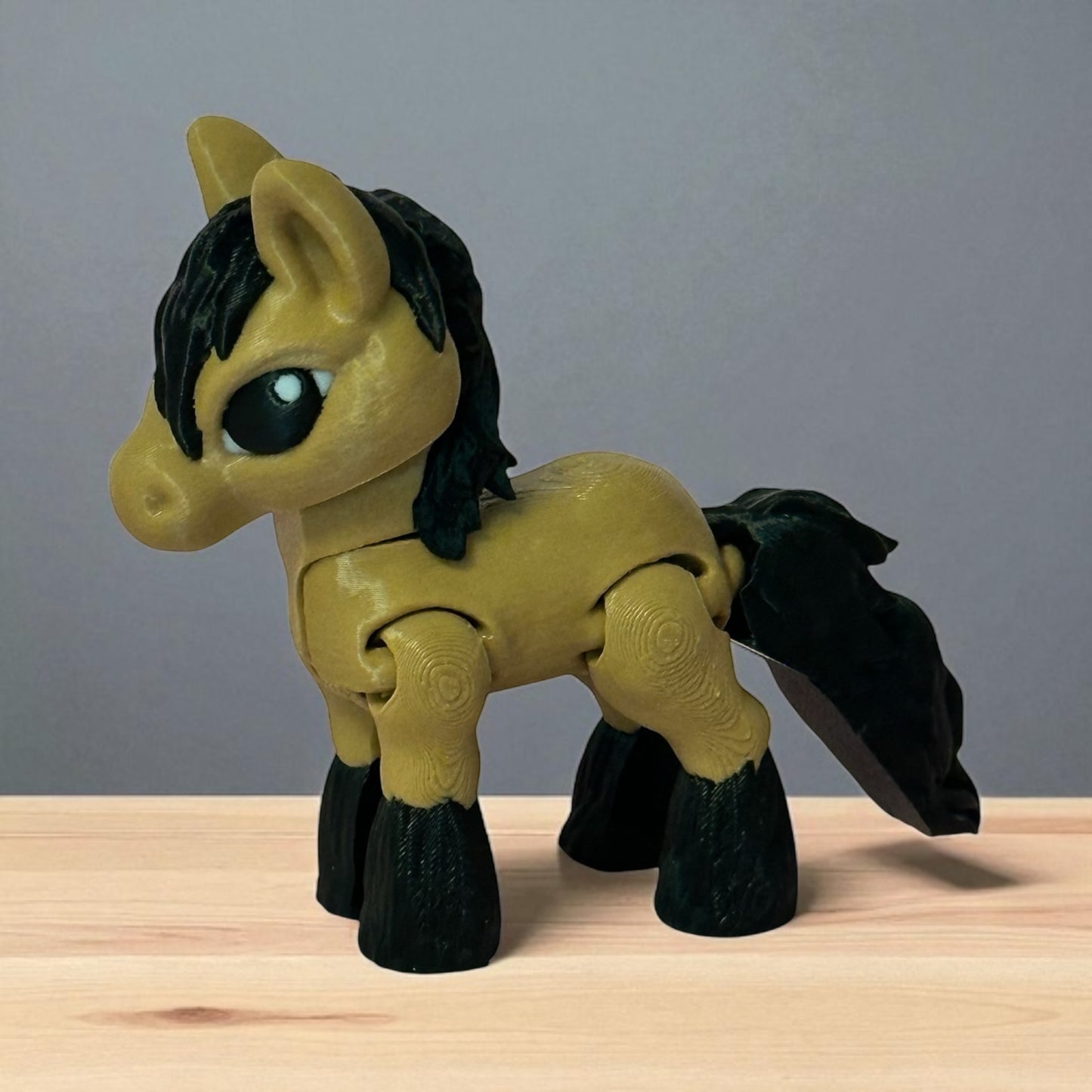 3d printed toy  brown horse figure with black mane and tail on a wooden surface and a gray background