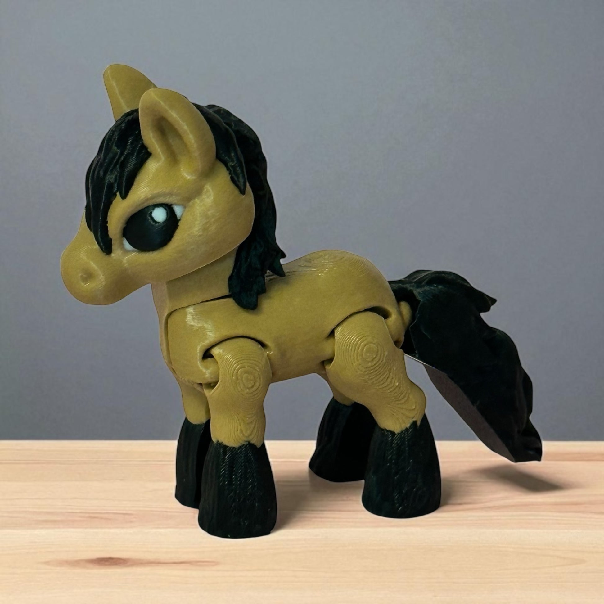 3d printed toy  brown horse figure with black mane and tail on a wooden surface and a gray background