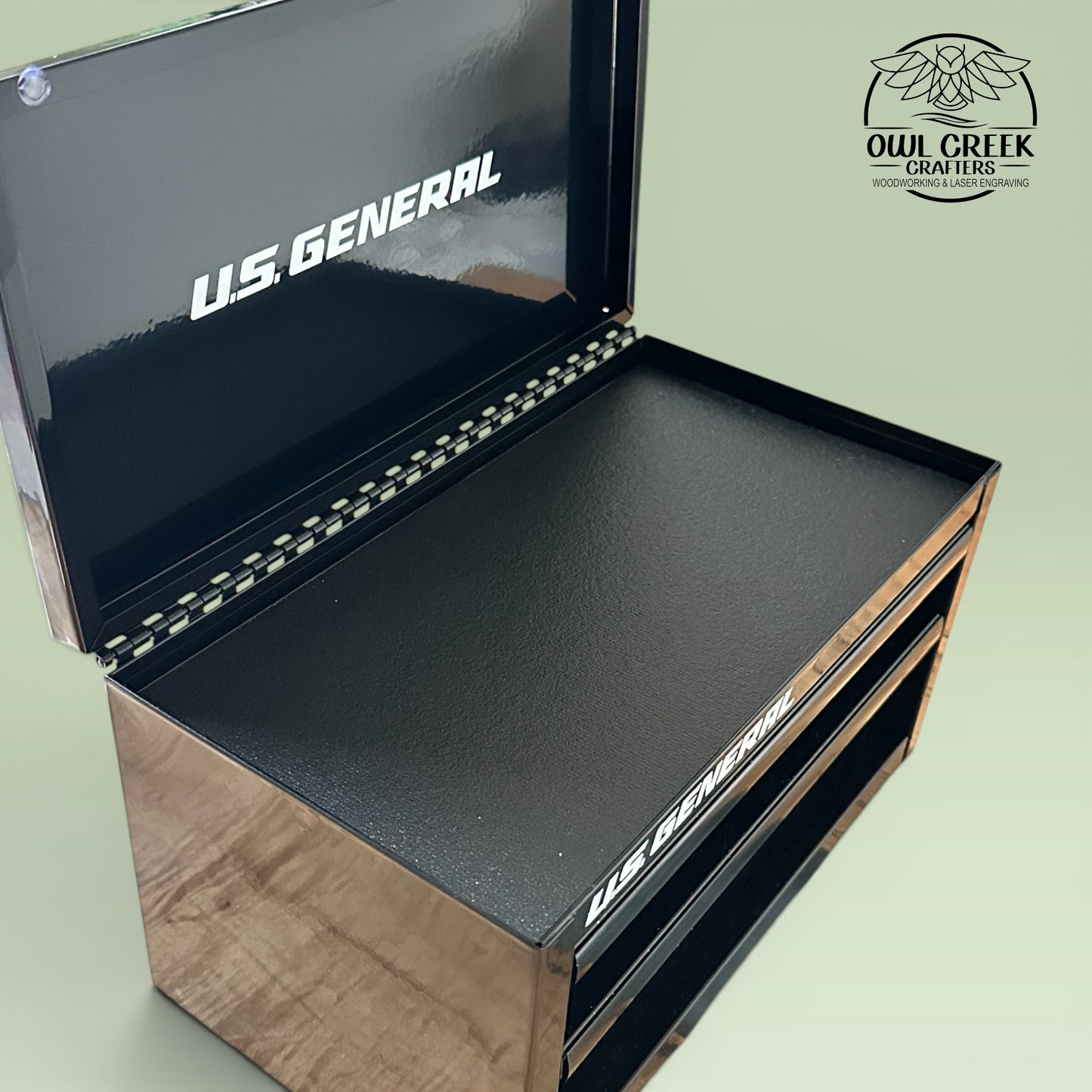 A black metal mini toolbox with the top lid openon a green background with the Owl Creek Crafters Logo in the corner