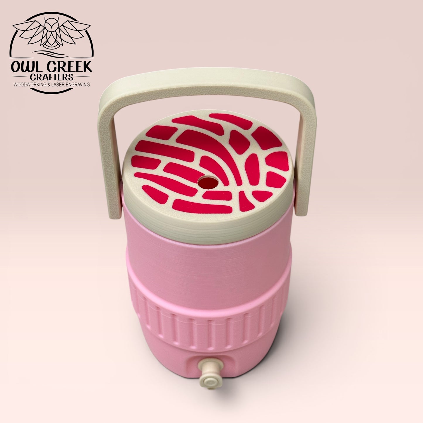 Pink can cooler coozie with a tan and  magenta lid and handle, on a beige background with the Owl Creek Crafters Logo