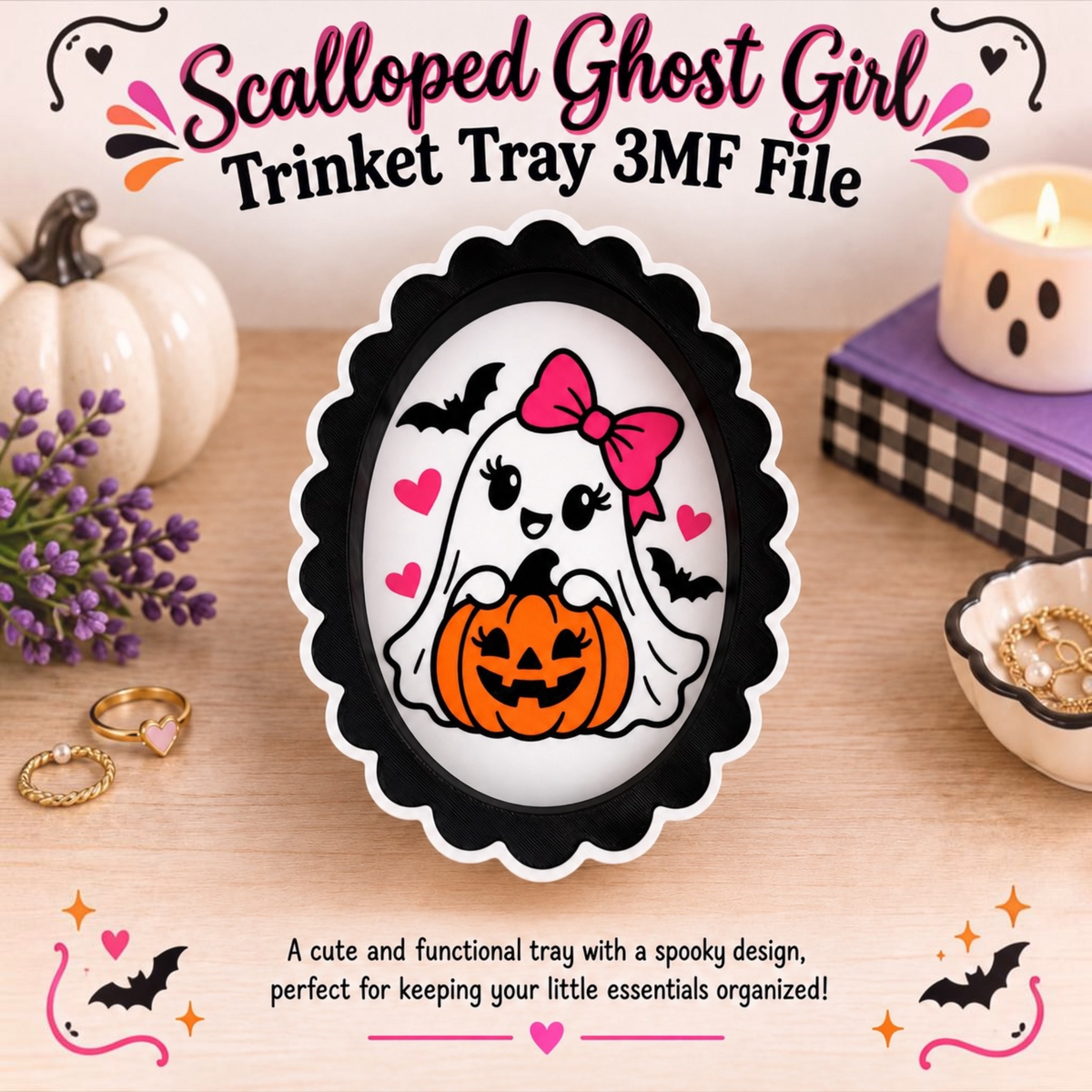 A Halloween-themed scalloped ghost-shaped ring tray shown on a wooden tabletop with decorative props. The tray has a black scalloped border and a white center featuring a cartoon ghost with a pink bow, holding an orange jack-o'-lantern, with pink hearts and black bats. In the top center is the words "Scalloped Ghost Girl Trinket Tray 3MF File". In the bottom center is the sentence "A cute and functional tray with a spooky design, perfect for keeping your little essentials organized!".