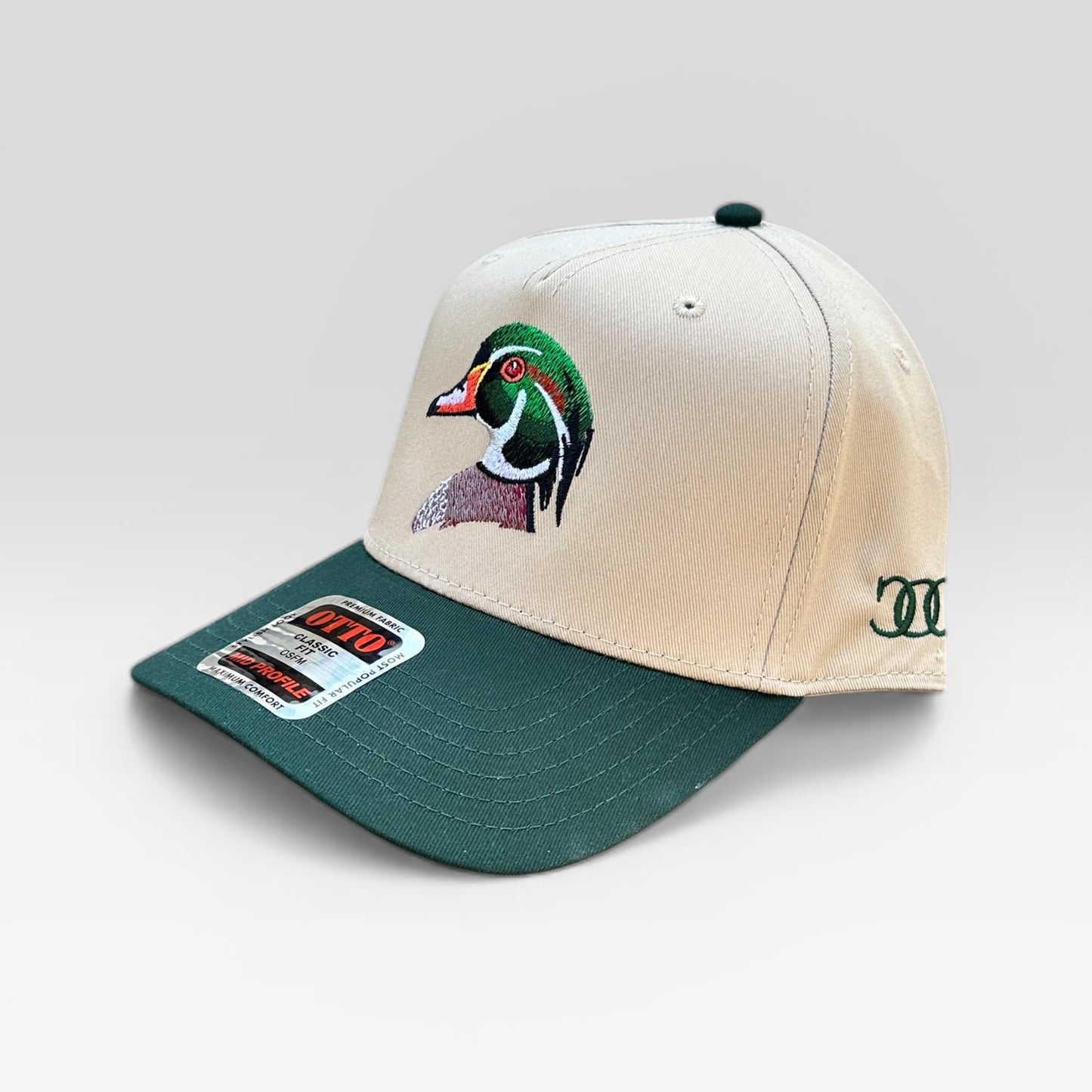 Beige and green cap with an embroidered wood duck logo on a light gray background