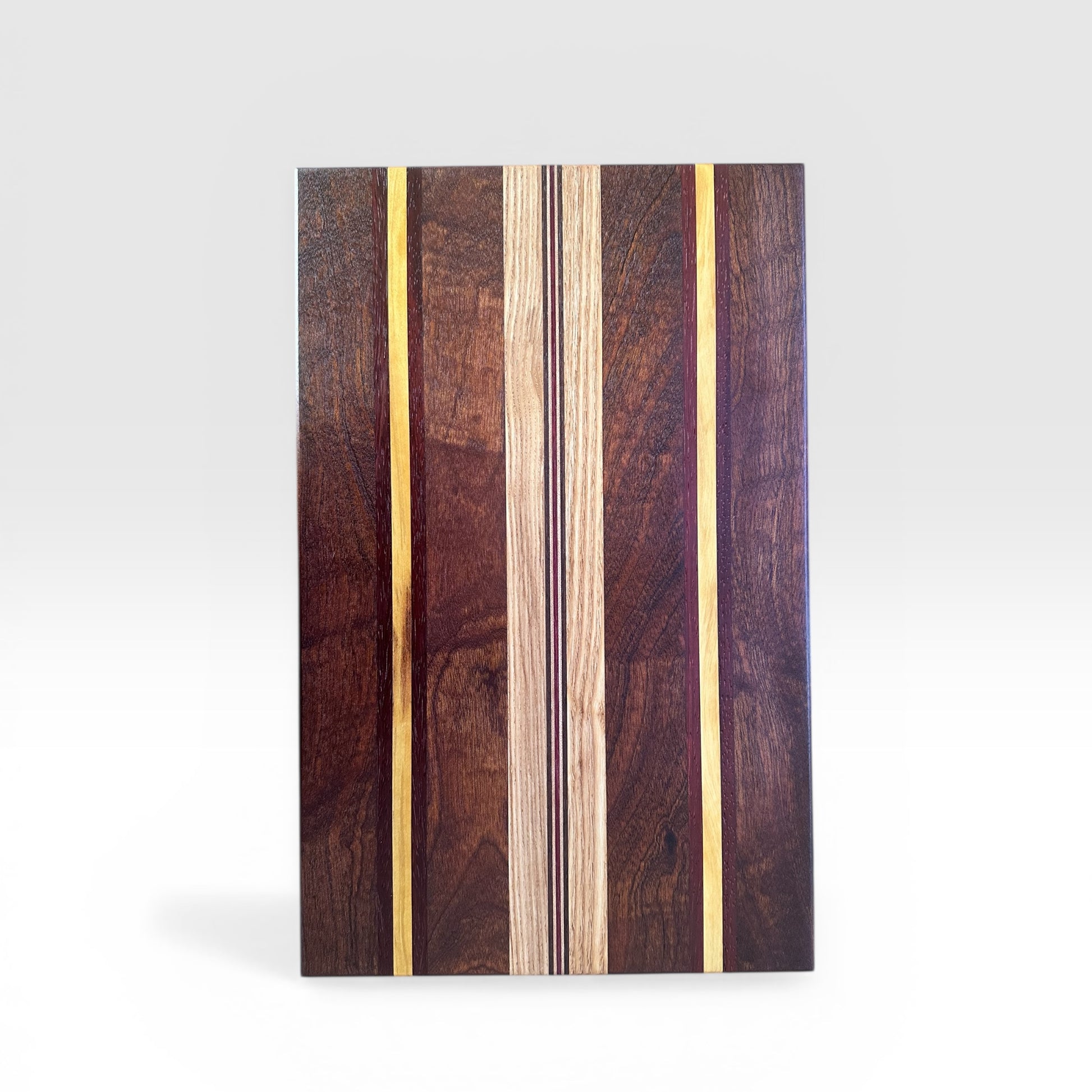 Wooden cutting board with a multi colored striped pattern on a white background