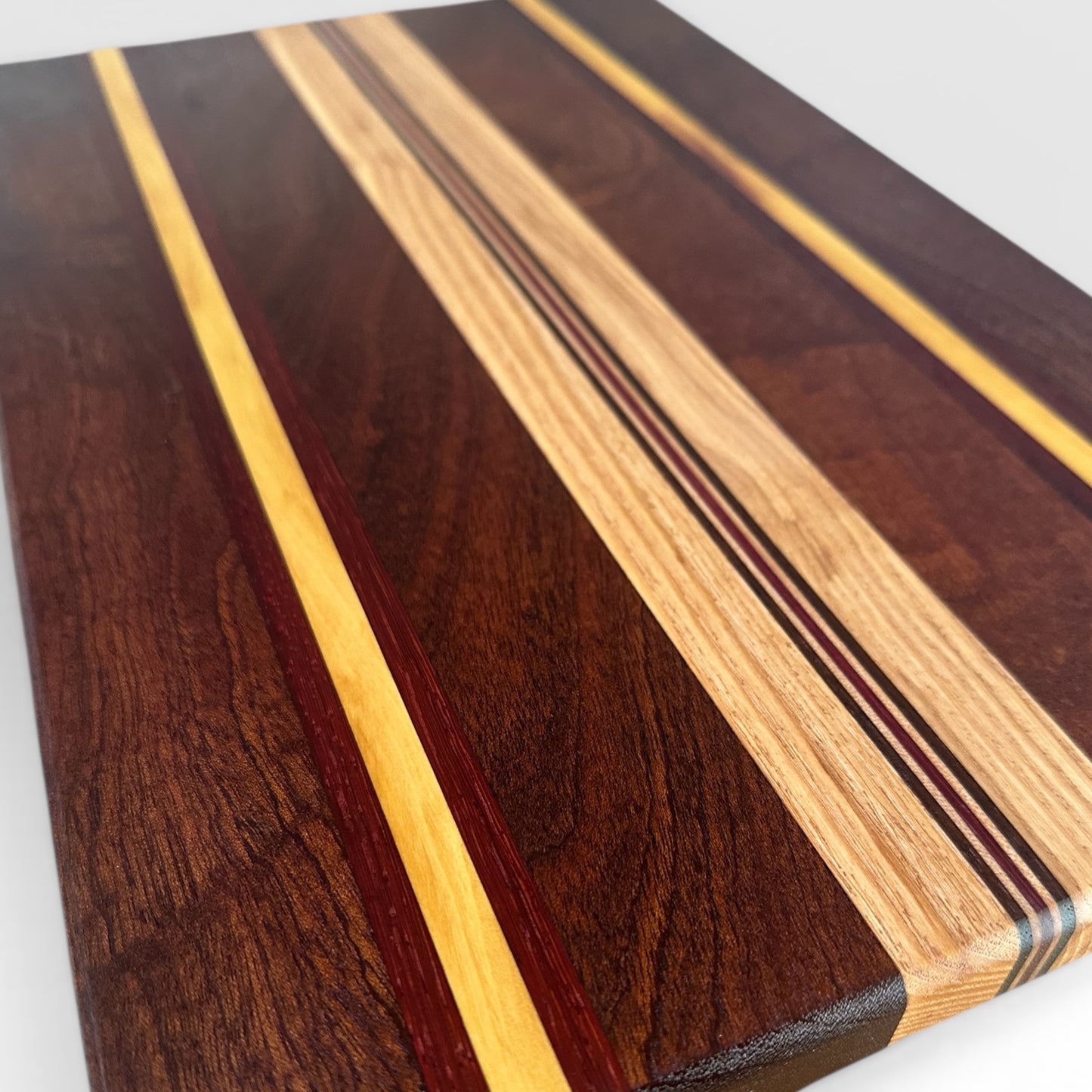 Wooden cutting board with a multicolored striped pattern on a white background